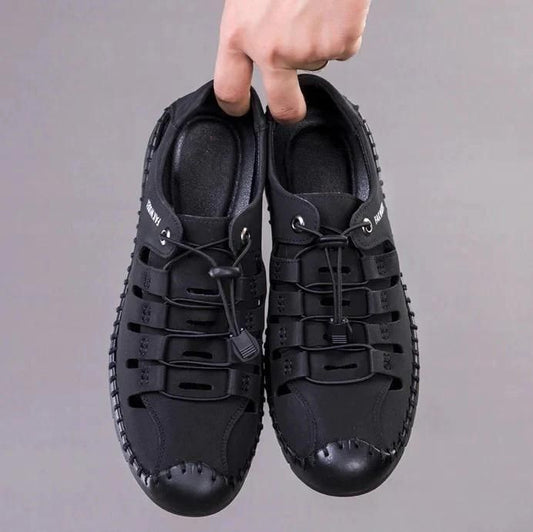 Black lightweight shoes held in hand, designed as comfortable casual shoes for men