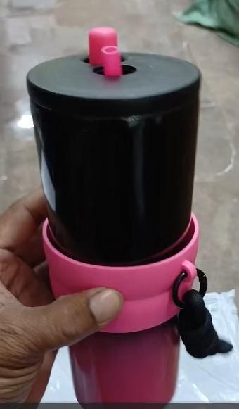 Hand holding a dual function tumbler with a black top and pink base, ideal for drinks on the go