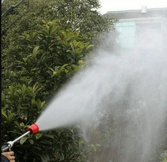 High-pressure spray gun for farming in action, delivering a powerful water stream among lush greenery