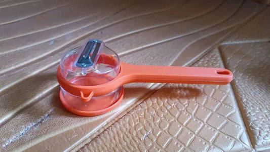 Multifunctional kitchen peeler in orange with a clear container for easy food preparation and storage