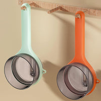 Multifunctional kitchen peeler in mint green and orange hanging on a kitchen wall for easy access